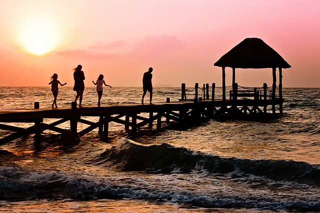 Family walking on pier by sunset