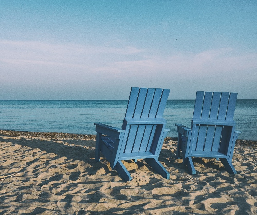 Blue chairs on beach facing sea