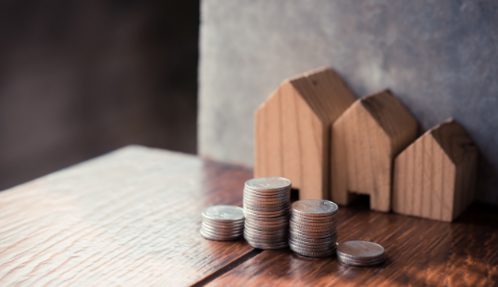 Small wooden houses next to coin stacks