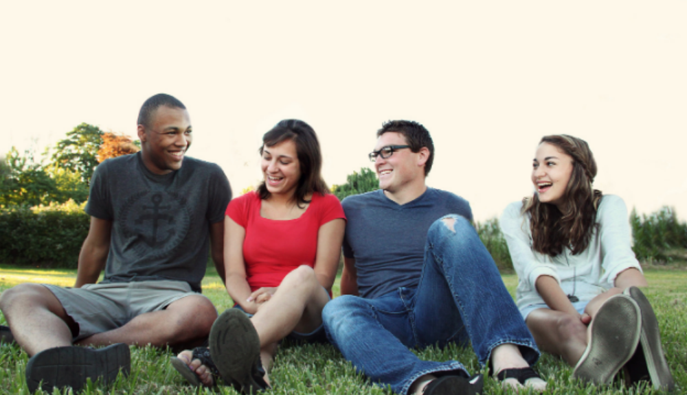 Young people sitting in garden smiling together